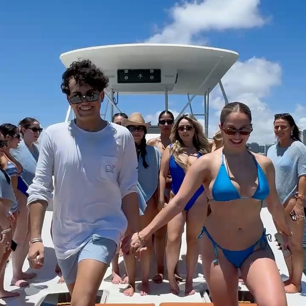 A group in swimwear on the bow under the hardtop, a couple walking hand in hand at the front