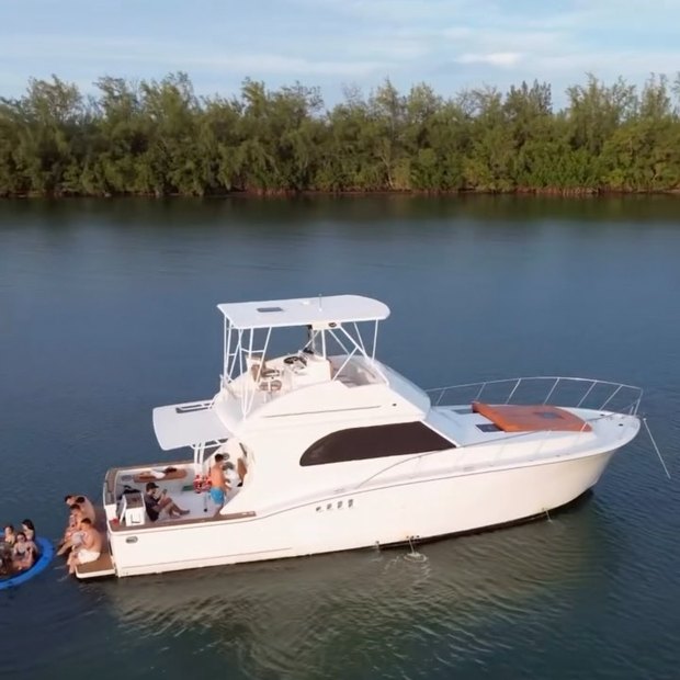The Chris Craft anchored close to a mangrove shoreline with guests on the bow and a float in the water